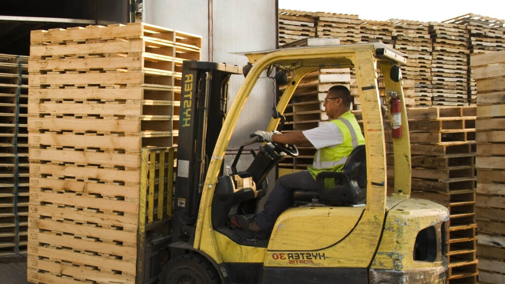 Forkliftle kaldırılan üst üste dizilmiş ikinci el paletler